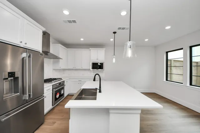 a kitchen with stainless steel appliances a sink a stove a refrigerator and cabinets