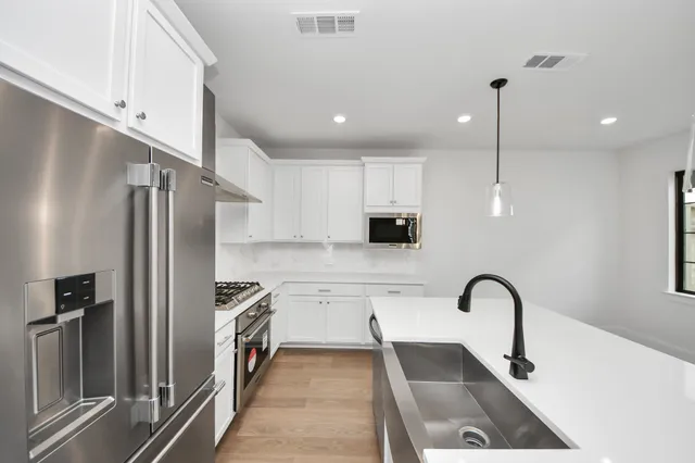 a kitchen with stainless steel appliances granite countertop a sink a stove and a refrigerator