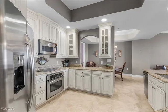 a kitchen with stainless steel appliances granite countertop a table chairs sink and cabinets