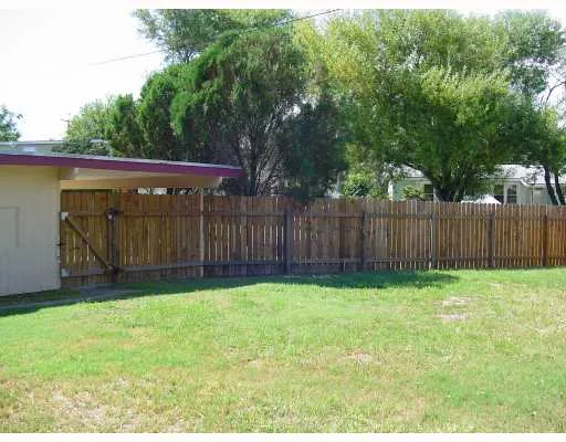 a view of backyard with wooden fence and trees