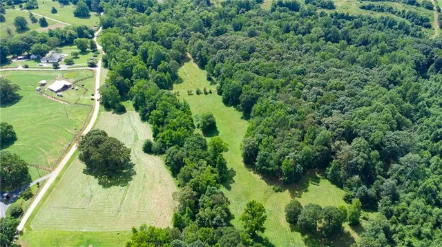 an aerial view of residential houses with outdoor space and trees all around