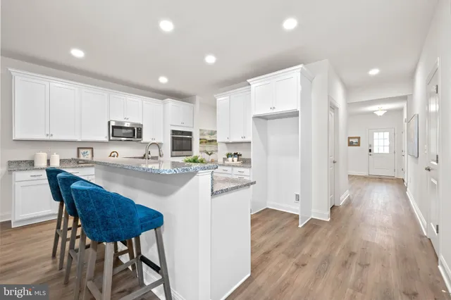 a kitchen with stainless steel appliances granite countertop a refrigerator a stove a sink dishwasher and a dining table with wooden floor