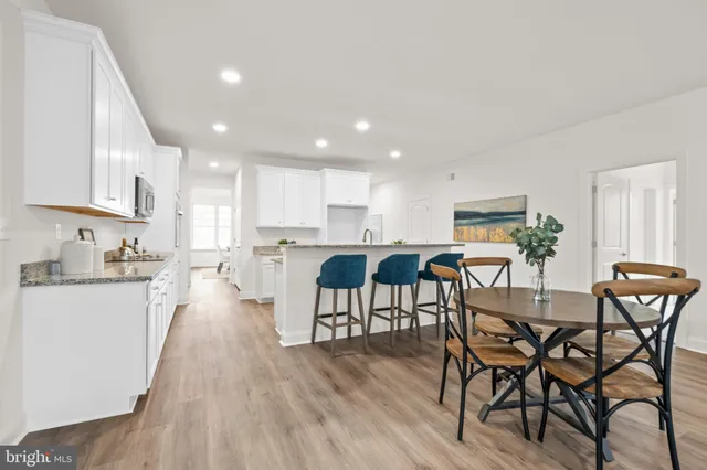 a kitchen with stainless steel appliances kitchen island granite countertop wooden floor a dining table and chairs