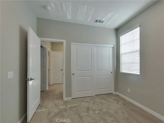 a view of an empty room with closet and a window
