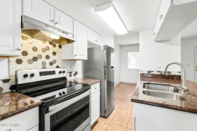 a kitchen with granite countertop a sink stove and refrigerator