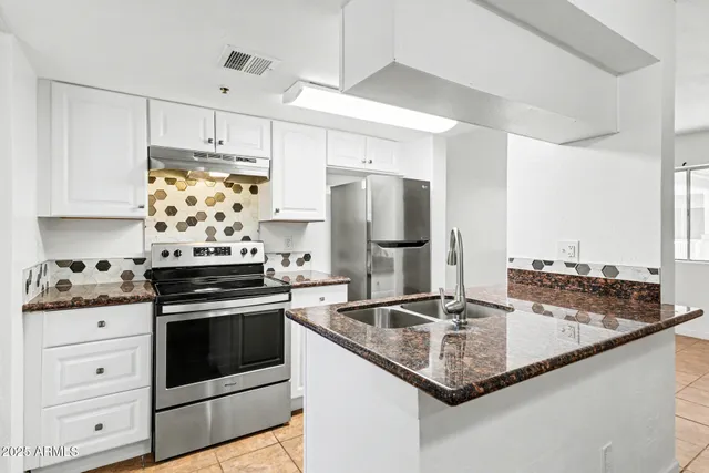 a kitchen with stainless steel appliances granite countertop a sink stove and refrigerator