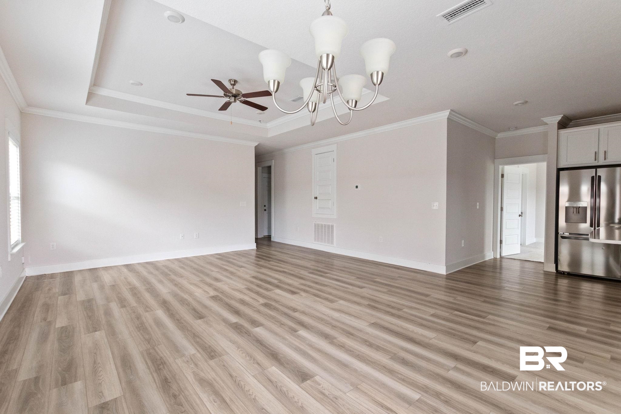 1710 Grouse Street Foley, AL 36535 - Photo 19 of 76 Expansive living area featuring wood-finish flooring, a tray ceiling with recessed lighting and a ceiling fan, and crown molding