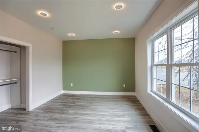 an empty room with wooden floor and windows