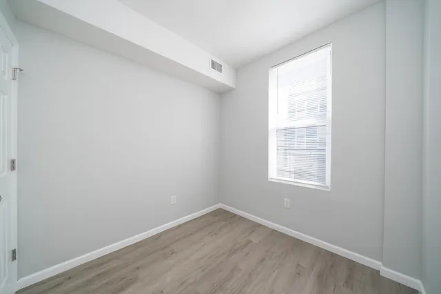 an empty room with wooden floor and windows