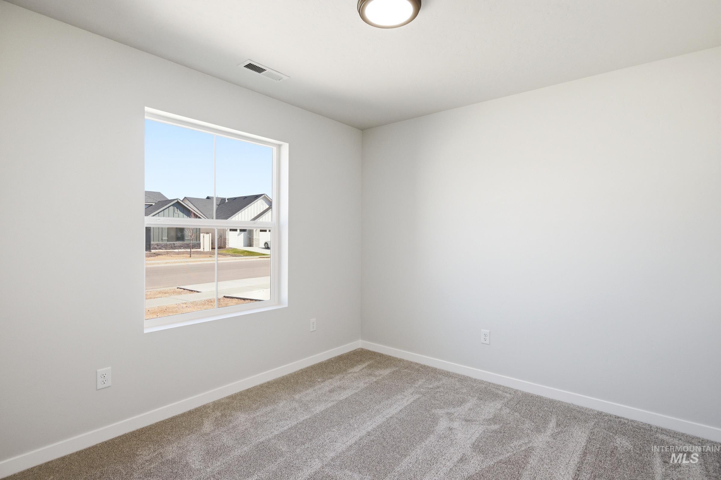 12877 Decatur Street Nampa, ID 83651 - Photo 16 of 22 Room featuring light gray carpet, white painted walls, a flush-mount ceiling light fixture, a rectangular window with white trim, and a white baseboard