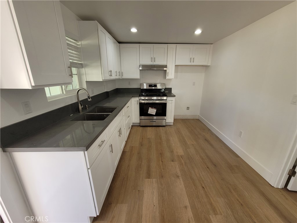 13564 4th Street, Unit 2 Yucaipa, CA 92399 - Photo 4 of 7 a kitchen with granite countertop a sink a stove and refrigerator