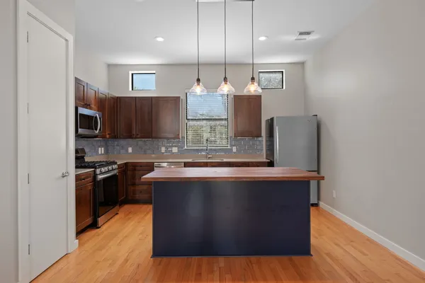 a kitchen with kitchen island stainless steel appliances a sink cabinets and wooden floor