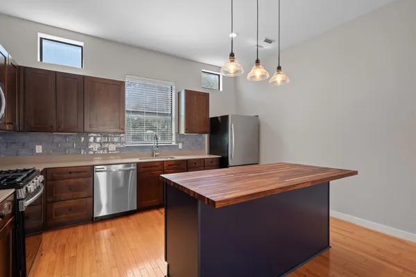 a kitchen with stainless steel appliances granite countertop wooden cabinets a refrigerator a sink and dishwasher