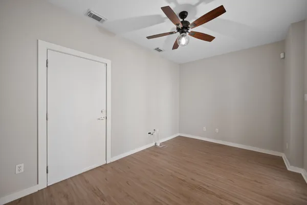 an empty room with wooden floor and a ceiling fan