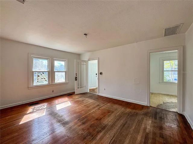 an empty room with wooden floor and windows