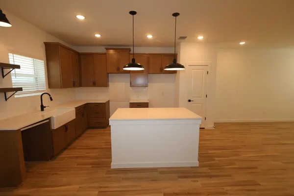 a view of a kitchen with kitchen island a sink wooden floor and a large window