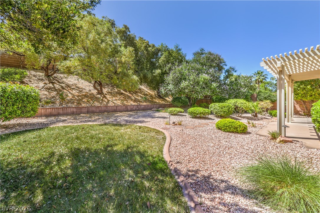 A well-maintained xeriscape garden with a slatted pergola invites outdoor leisure.