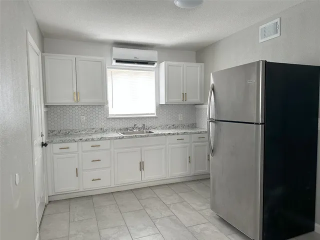 a kitchen with granite countertop cabinets and refrigerator