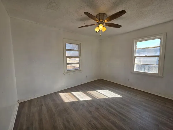 an empty room with wooden floor and windows