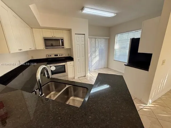 a kitchen with a sink a stove and white cabinets