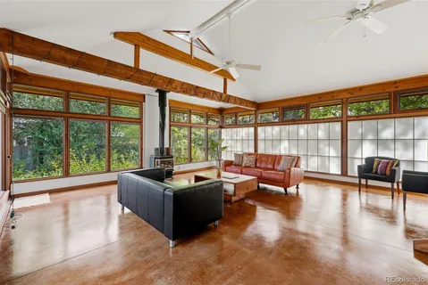 a living room with furniture large windows and wooden floor