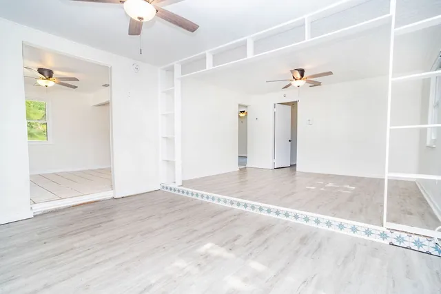 a view of an empty room with window and wooden floor
