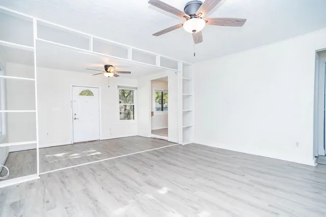 a view of an empty room with window and wooden floor
