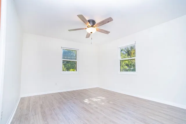 an empty room with wooden floor and ceiling fan