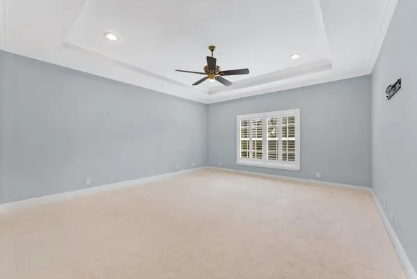 an empty room with chandelier fan and windows