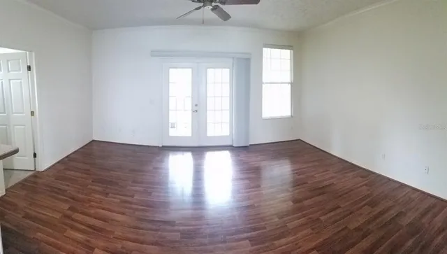 an empty room with wooden floor and windows