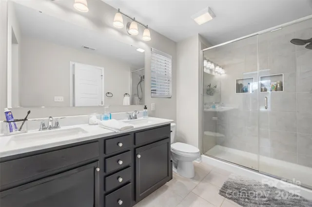 a bathroom with a double vanity sink toilet mirror and shower