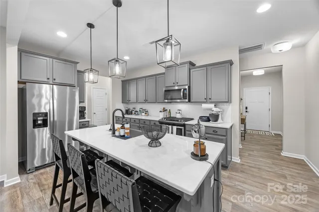 a kitchen with stainless steel appliances granite countertop a sink a stove a refrigerator and chairs