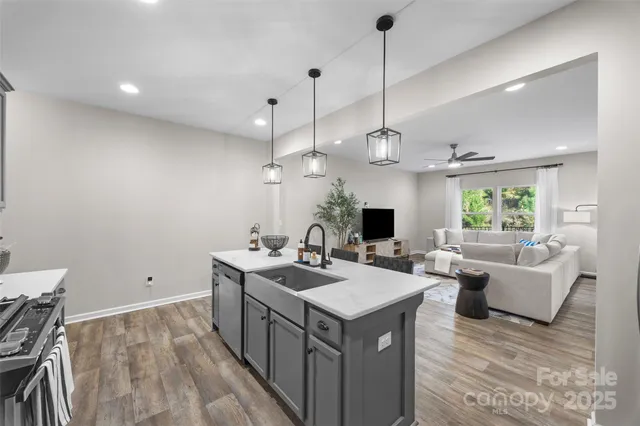 a view of a kitchen with kitchen island a sink a counter top space and living room view