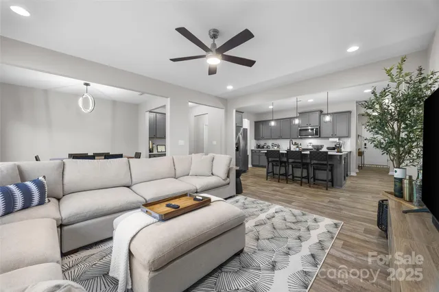 a living room with furniture and kitchen view with wooden floor