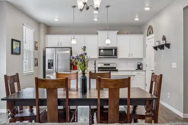 a dining room with stainless steel appliances kitchen island granite countertop a dining table chairs and a refrigerator