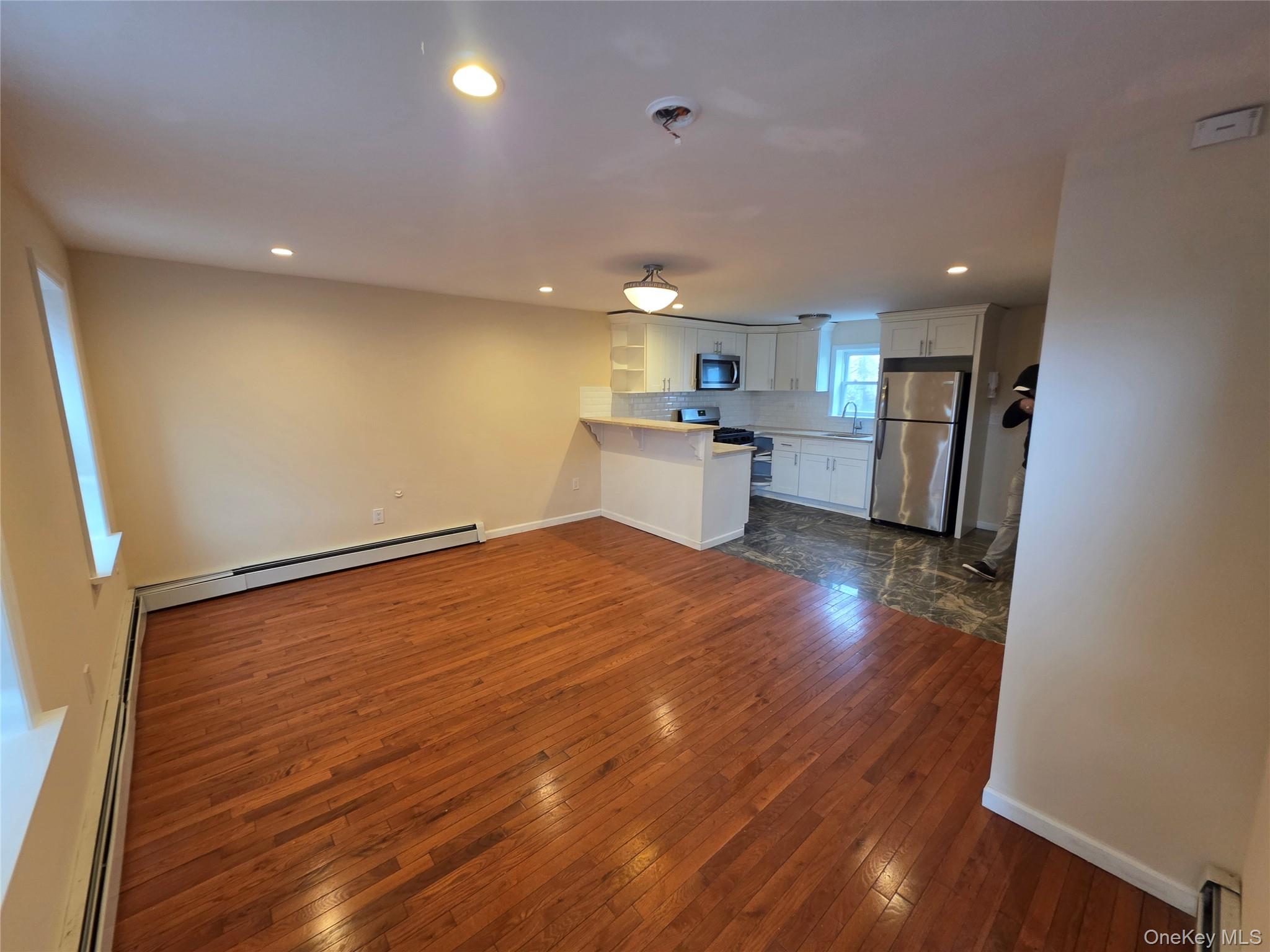 42 Hasbrouck Street Newburgh, NY 12550 - Photo 2 of 8 a open kitchen with a sink dishwasher refrigerator stove and wooden floor