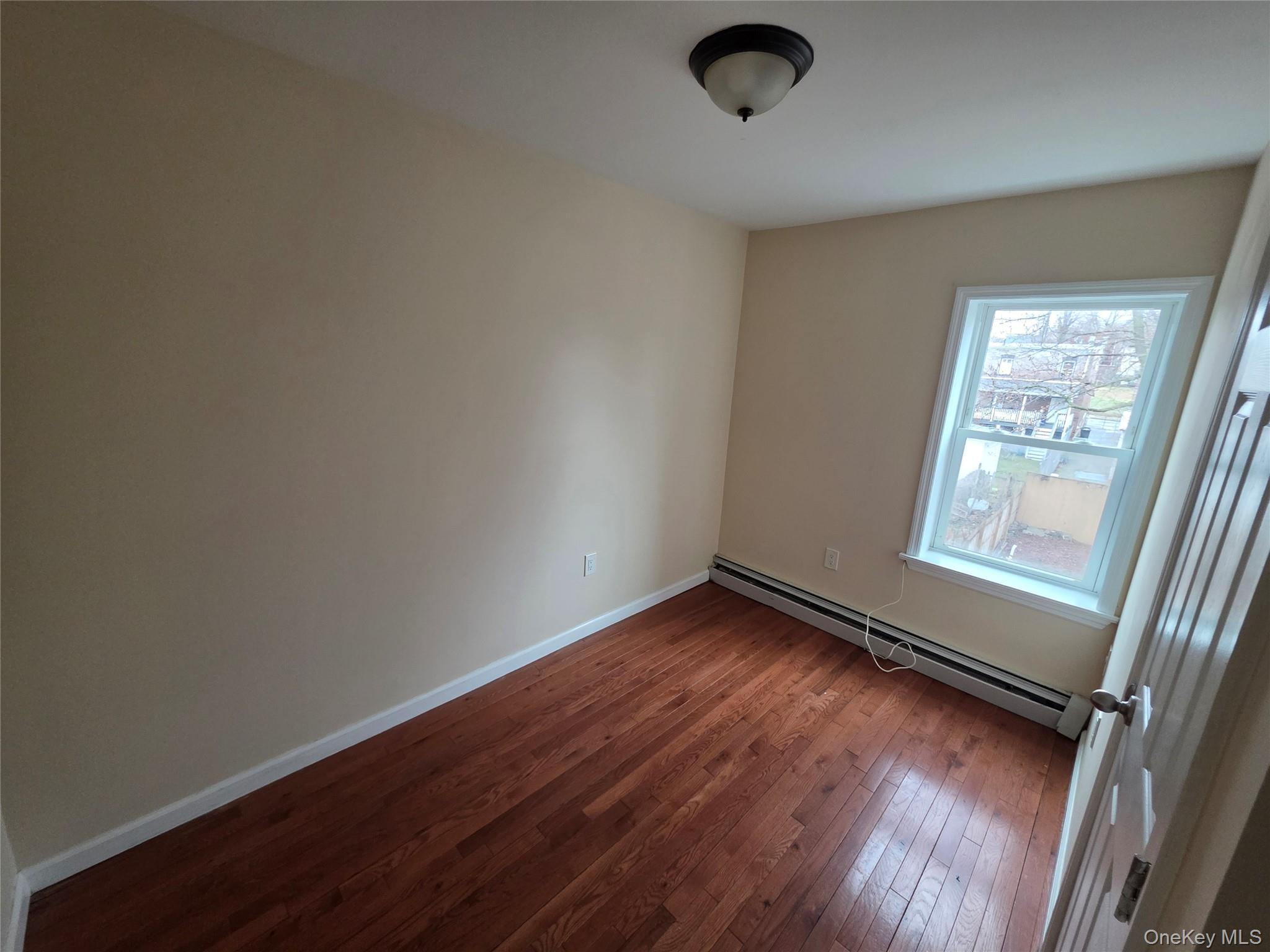 42 Hasbrouck Street Newburgh, NY 12550 - Photo 6 of 8 an empty room with wooden floor and windows
