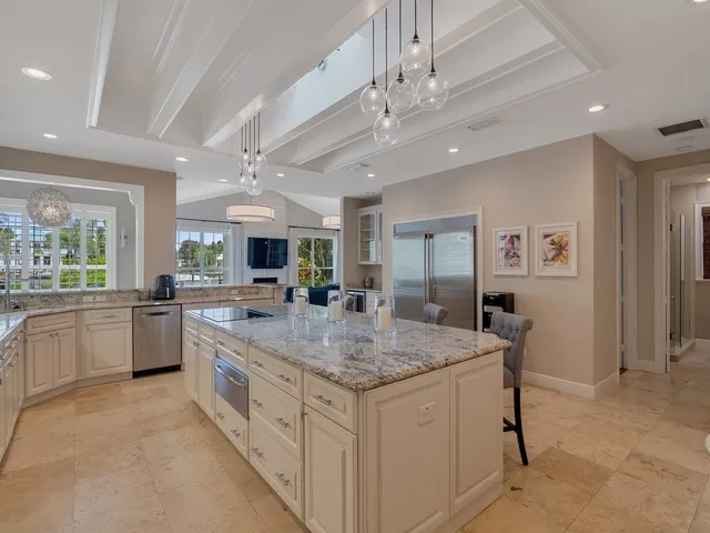 a kitchen with stainless steel appliances granite countertop a stove top oven a sink dishwasher a dining table and chairs with wooden floor