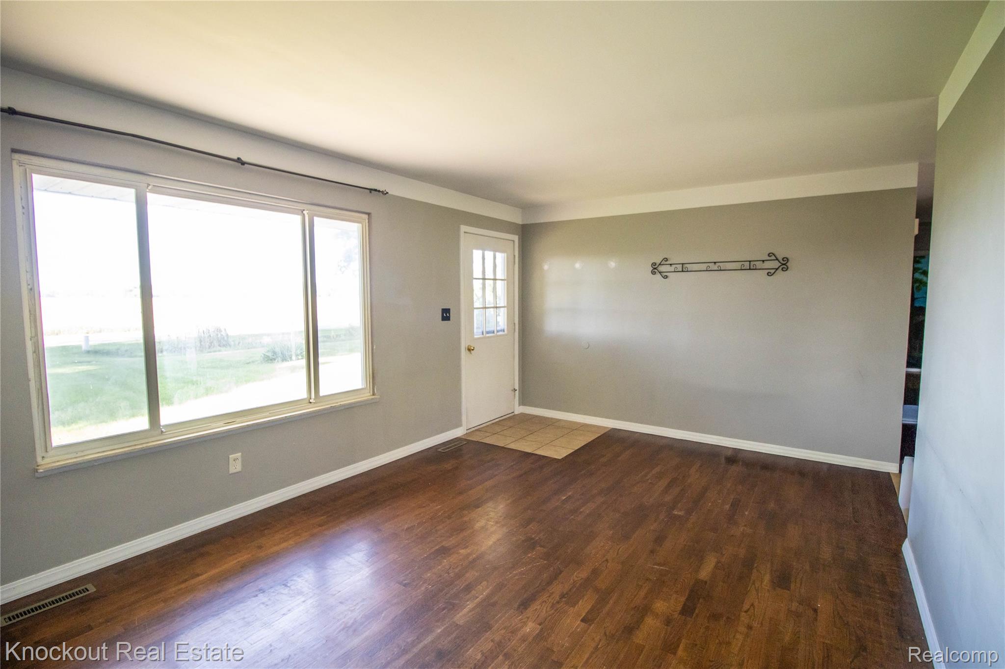 5796 East Burt Road Birch Run, MI 48415 - Photo 5 of 41 Wood-finish flooring, white trim, large window, and light gray wall paint