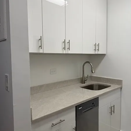 a kitchen with granite countertop white cabinets and a sink