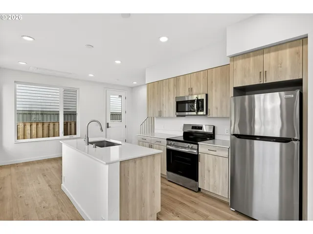 a kitchen with refrigerator a sink a stove and cabinets