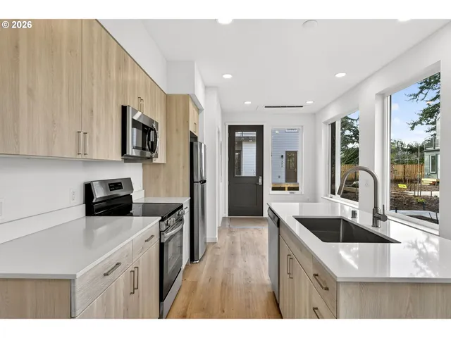 a kitchen with stainless steel appliances kitchen island granite countertop a sink and dishwasher a stove top oven with wooden floor