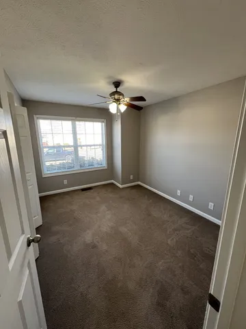 an empty room with a window and a fan