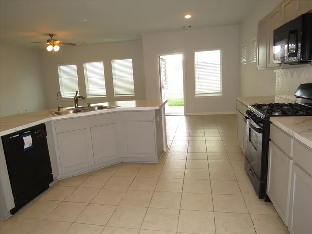 a large kitchen with stainless steel appliances a stove a sink a window and white cabinets