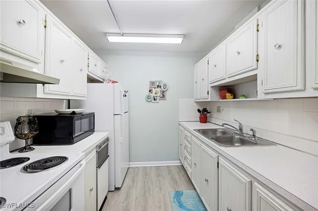 a kitchen with white cabinets and white appliances