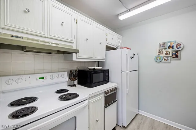 a kitchen with white cabinets and white appliances