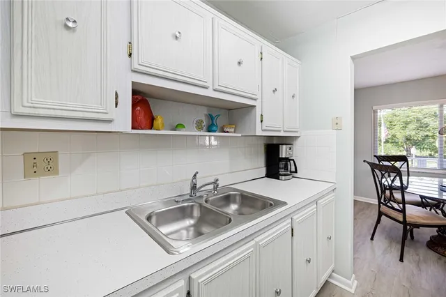 a kitchen with stainless steel appliances granite countertop a sink a stove and white cabinets