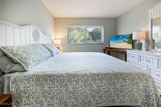 a bedroom with a bed a dresser and next to a window