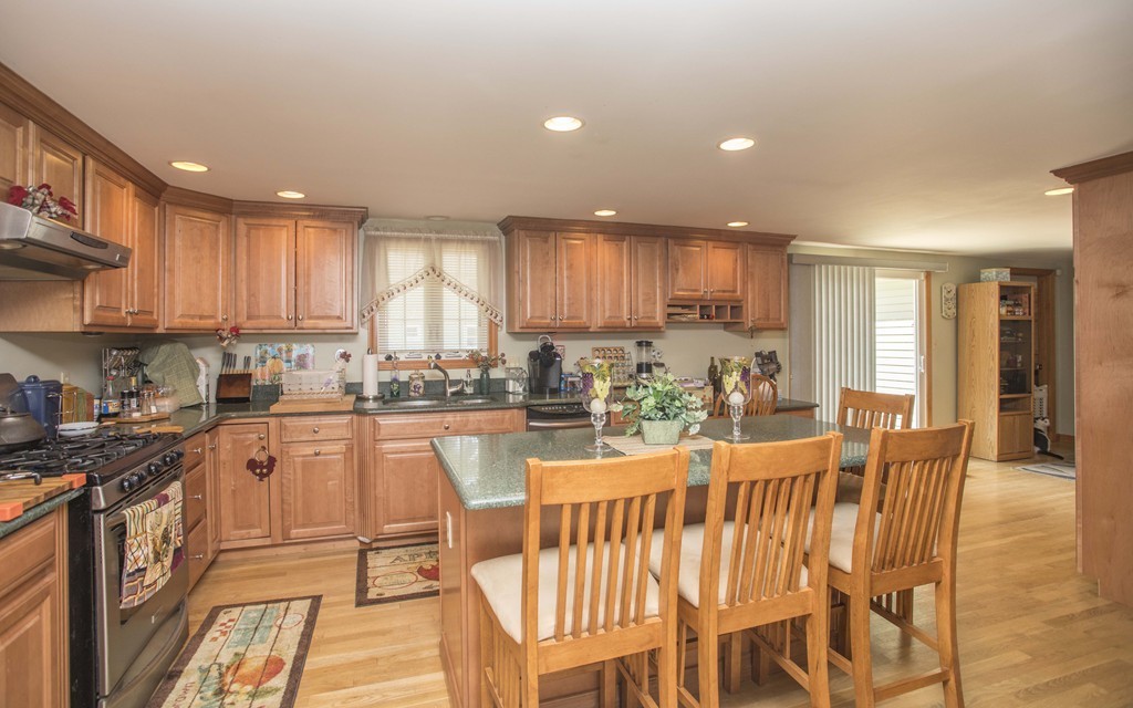 201 Riley Avenue Somerset, MA 02726 - Photo 7 of 22 a kitchen with stainless steel appliances granite countertop a stove top oven a sink a dining table and chairs with wooden floor
