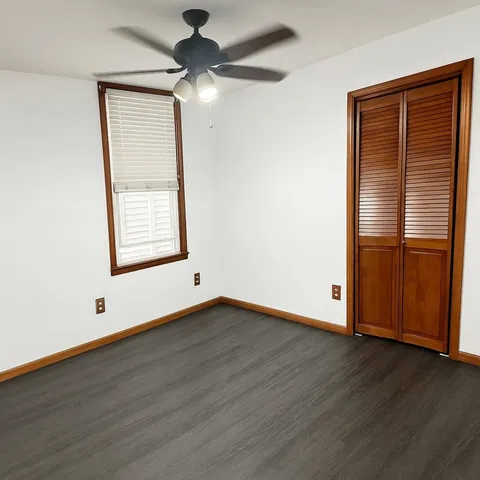 an empty room with wooden floor cabinet and windows
